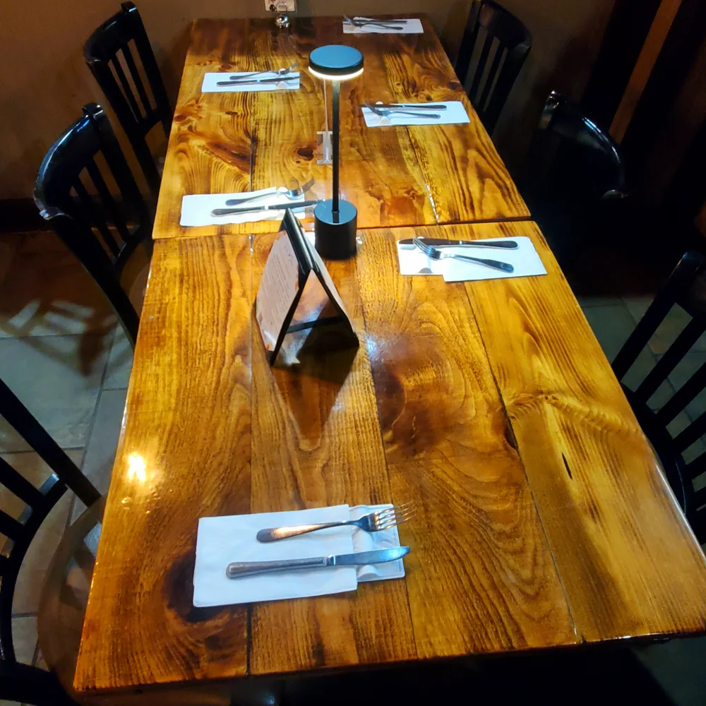 A long wooden dining table set with white LIFSTR utensil rests, knives, forks, and folded napkins.